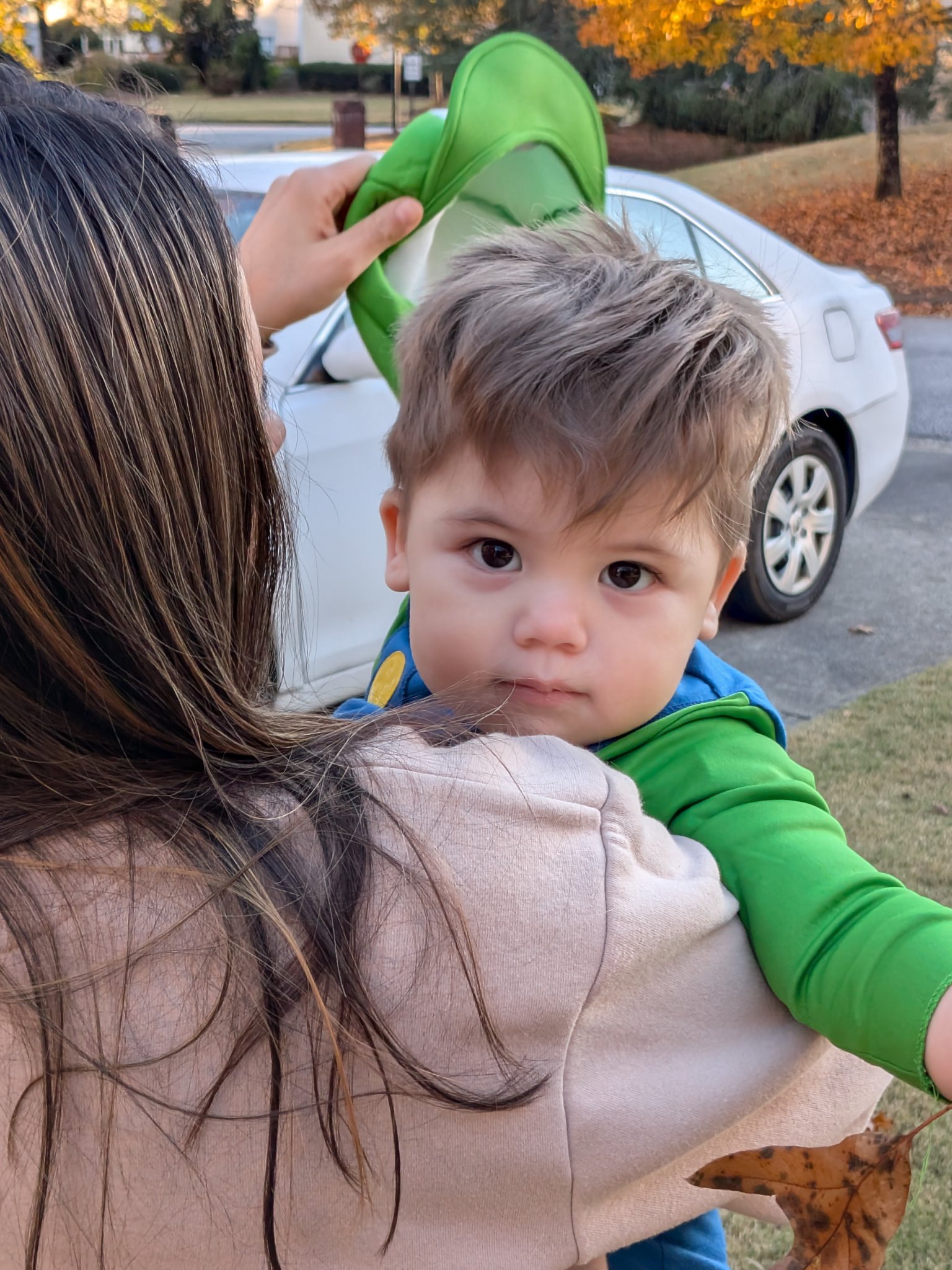 First Halloween trick-or-treating with my grandchildren — Luigi over his mom&rsquo;s shoulder, looking at the camera, Fri · Oct 31, 2025